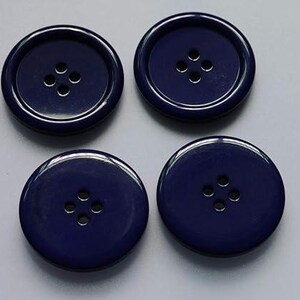 May include: Four navy blue buttons with four holes each. The buttons are round with a glossy finish and a raised outer rim. These buttons are suitable for sewing projects.