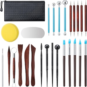 May include: A comprehensive pottery and sculpting tool set. Includes a black zippered case, a yellow sponge, a metal smoothing tool, blue and silver ball tools, wooden tools, and various sculpting tools with blue tips.