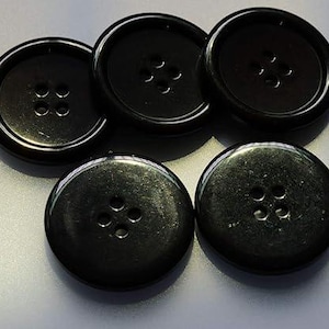 May include: Five black plastic buttons with four holes each. The buttons are round and have a smooth, glossy finish.
