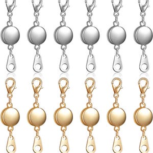 May include: A collection of jewelry clasps in silver and gold tones. Each clasp features a round magnetic closure, a lobster claw clasp, and a teardrop-shaped connector. The clasps are designed for jewelry making and repair.