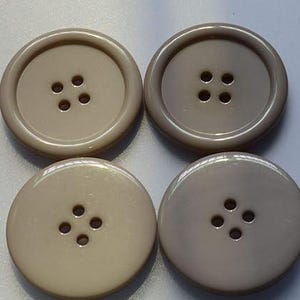 Puede incluir: Cuatro botones de plástico beige con cuatro agujeros cada uno.