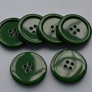 May include: Five green plastic buttons with four holes each. The buttons are round and have a glossy finish.