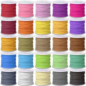 Op de afbeelding: Een verzameling kleurrijke suède koorden gewikkeld op witte spoelen. De koorden zijn in verschillende tinten, waaronder rood, roze, paars, oranje, geel, groen, blauw, grijs en bruin. Deze koorden worden waarschijnlijk gebruikt voor het maken van sieraden of knutselen.