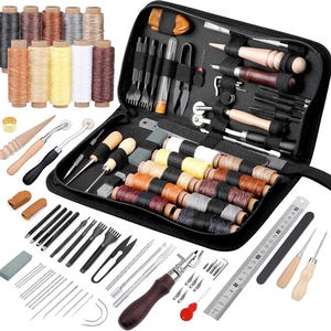 May include: A black leather sewing kit containing a range of tools, including needles, thread, awls, and a hammer. The kit also features a selection of coloured threads and a ruler.