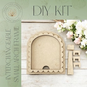 May include: A DIY kit for a small, interchangeable arch frame. The frame is made of unfinished wood with a scalloped edge. The kit includes the frame, a stand, and several small wooden pieces. The text "DIY KIT" is at the top.