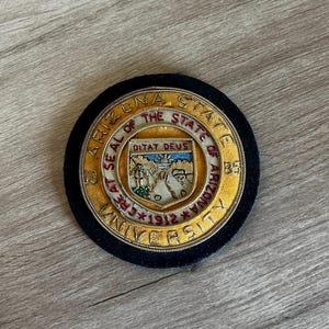 May include: Circular embroidered patch featuring the Arizona State University seal. The patch has a black background with gold and red detailing. The text "SEAL OF THE STATE OF ARIZONA" and "ARIZONA STATE UNIVERSITY" are visible.