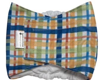 May include: A plaid belly band featuring a multi-colored pattern of blue, yellow, green, and orange stripes on a white background. The wrap has a white interior lining and a white fabric tag with the text handsewnbyne www.etsy.com attached.