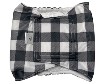 May include: A black and white buffalo plaid pet diaper with a white interior. The diaper has a rectangular shape with a hook and loop closure and a tag that reads "FuzzyAndToo" and "www.etsy.com".