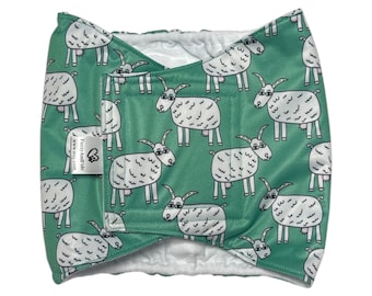 May include: A green fabric wrap with a white goat pattern. The wrap has a white interior and a small tag with text. The wrap is designed to be secured with a hook and loop closure.