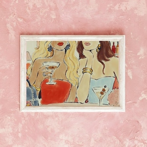 May include: A framed painting depicting two individuals with long hair, one blonde and one brunette, wearing red and blue tops. They are holding martini glasses with olives. The blonde individual wears a ring and bracelet, while the brunette wears gold earrings and a thick gold bracelet.