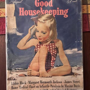 May include: Vintage August issue of Good Housekeeping magazine. The cover features a young girl in a red and white star-patterned swimsuit holding a seashell to her ear. The magazine is sealed in plastic.