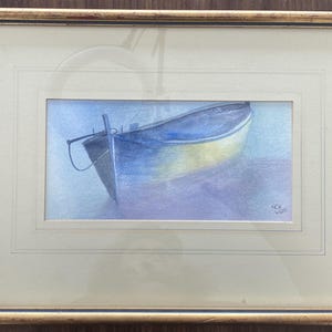 May include: Watercolour painting of a small boat in shades of blue and yellow, framed in a gold-toned frame. The boat is depicted in a serene, aquatic setting, with soft, blended colours. The artwork is signed in the lower right corner.