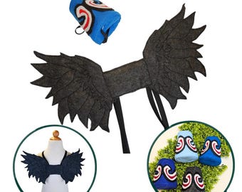May include: A set of dark gray felt wings with jagged edges and black straps, accompanied by blue and gray cylindrical cuffs featuring a white, red, and black swirl design. The wings are shown on a mannequin and the cuffs are displayed separately.