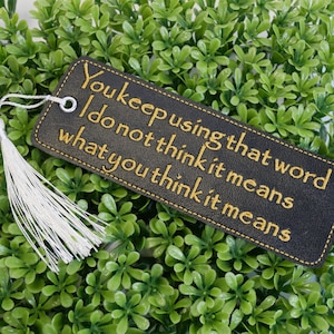 May include: A black leather bookmark with a gold embroidered quote: "You keep using that word. I do not think it means what you think it means."