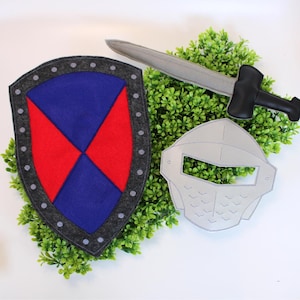 May include: A felt knight's shield with a red and blue design, a grey sword with a black handle, and a grey helmet. The shield has a grey border with grey rivets. The toy set is designed for imaginative play.