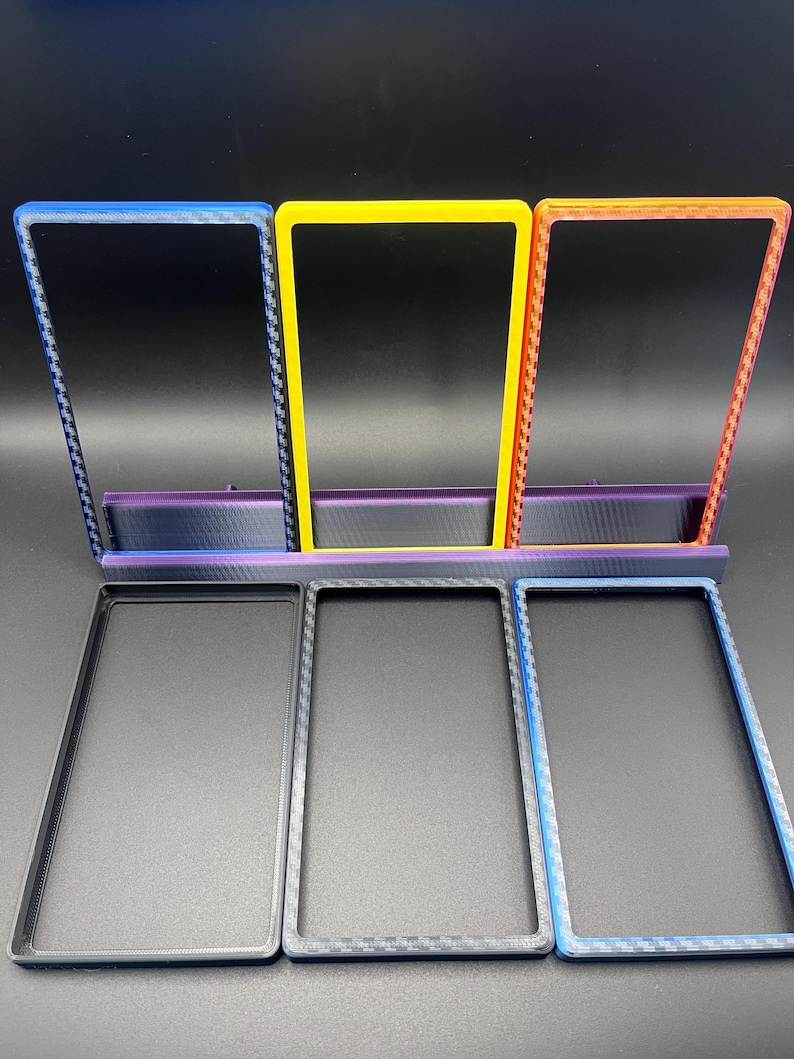 May include: A set of six rectangular frames in various colors. Three frames are upright, in blue, yellow, and orange, and three are flat, in black, gray, and blue. All frames have a textured pattern on the edges.