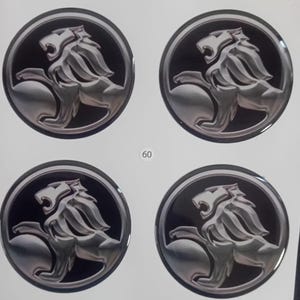 May include: Four circular stickers with a silver lion rampant emblem on a black background. The lion is detailed with flowing mane and muscular form, set within a silver border. The number "60" is printed in white.