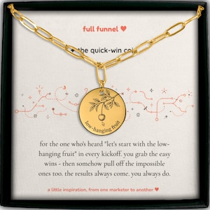 Può includere: Una collana color oro con un ciondolo circolare che presenta un ramo di ciliegio inciso e il testo "low-hanging fruit". Il ciondolo è esposto su un cartoncino con il testo "full funnel", "the quick-win coin" e un paragrafo di testo.
