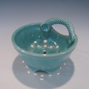 May include: A set of three ceramic mugs with a speckled, matte finish. The mugs are in shades of cream, light gray, and dark gray. Each mug has a simple, modern design and a comfortable handle.