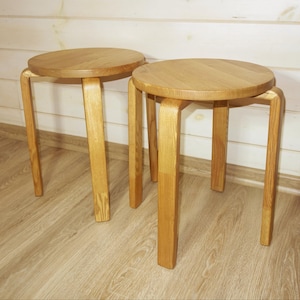 Puede incluir: Dos taburetes de madera con asientos redondos y patas curvas. Los taburetes son de madera de color claro y tienen un diseño simple y minimalista. Los asientos tienen aproximadamente 30 cm de diámetro.