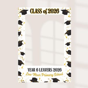 May include: A rectangular photo booth frame featuring a white background with black graduation caps and gold confetti. The top text reads CLASS of 2026, and the bottom text reads YEAR 6 LEAVERS 2026 Low Moor Primary School in black and gold.