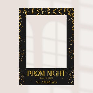 May include: Black photo booth prop with gold confetti and streamers. The text reads "Prom Night Class Of 2025 St. Andrews" in gold lettering. The frame has a white centre for taking photos.