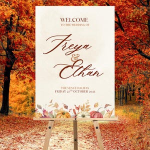 May include: A wedding welcome sign on an easel. The sign reads "Welcome to the wedding of Freya & Ethan" in elegant script. The venue is Halifax, and the date is Friday 27th October 2025. The bottom of the sign features a watercolour design of pumpkins and autumn foliage.