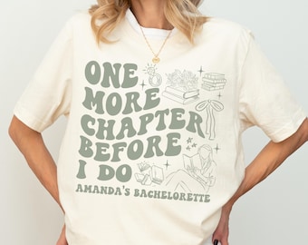 May include: Cream-colored t-shirt with the text "ONE MORE CHAPTER BEFORE I DO" in green, along with illustrations of books and a ring. The text "AMANDA'S BACHELORETTE" is below. The model is wearing size XL.