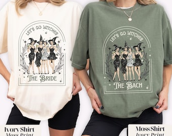 May include: Two oversized t-shirts, one ivory and one moss green, each featuring a graphic of stylized witches. The ivory shirt says "The Bride," and the moss green shirt says "The Bach." Both shirts have the text "Let's Go Witches."