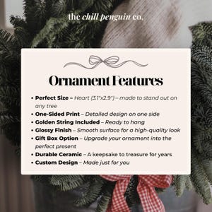 May include: Cream-colored card with the text "Ornament Features" and bullet points describing the product. The text includes "Perfect Size - Heart (3.1"x2.9")", "Golden String Included", and "Durable Ceramic". The background includes Christmas tree branches.