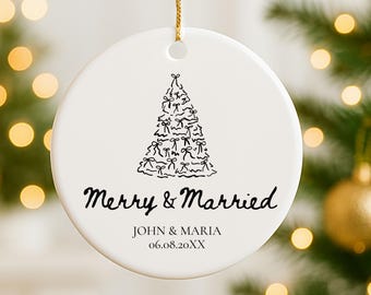 May include: White ceramic Christmas ornament with a gold string. The ornament features a black line drawing of a Christmas tree made of bows, with the words "Merry & Married" and a personalized name and date.
