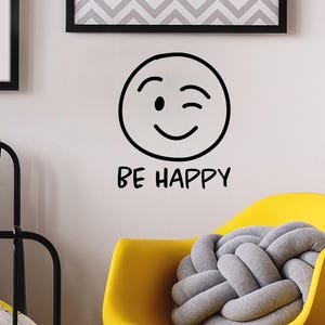 May include: Black and white wall decal with a winking smiley face and the text "BE HAPPY".