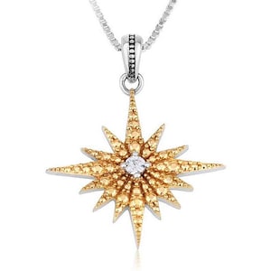 May include: A silver necklace with a pendant shaped like a golden starburst. The starburst is studded with small, yellow-gold gems and a single, clear gem in the center. The necklace chain is a delicate silver.