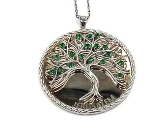 May include: Silver-toned pendant necklace featuring a detailed tree of life design. The pendant has a circular shape with a textured border and small green gemstones. The tree's branches and leaves are intricately crafted.