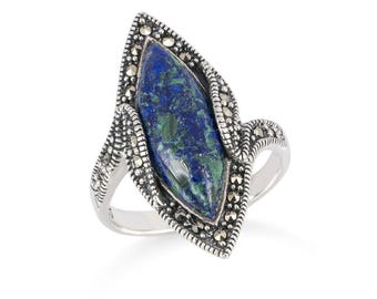 May include: A silver ring featuring a marquise-cut gemstone with blue and green hues. The gemstone is set within a decorative frame with small, round accents. The ring has a polished band.