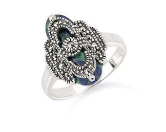May include: A silver ring featuring an oval-shaped, blue-green stone, intricately detailed with a silver filigree design. The ring's band is smooth and polished, creating a contrast with the textured centerpiece. The ring is set against a white background.