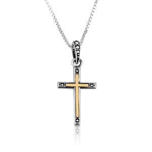 May include: A silver-toned necklace with a cross pendant. The cross features a gold-colored center and decorative black accents. The chain is a delicate, linked design, and the pendant is centered in the frame.