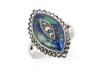 May include: A silver ring featuring an oval-shaped, blue and green stone with a marcasite border. The ring's design includes a smaller marcasite-accented oval within the larger stone, creating a striking contrast. The ring is set against a white background.