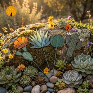 Op de afbeelding: Decoratieve tuinpalen met cactus- en vetplantontwerpen. De houten palen zijn beschilderd met levendige kleuren, waaronder oranje, groen en blauw. De palen zijn gerangschikt tussen echte vetplanten en bloemen, waardoor een natuurlijke tuinscène ontstaat.