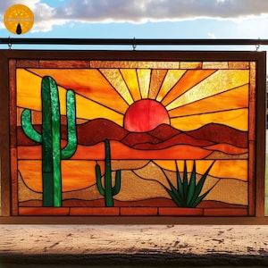May include: Stained glass panel showing a desert sunset. The artwork features a red sun, with rays, above brown mountains and green cacti. The panel is framed in dark wood.