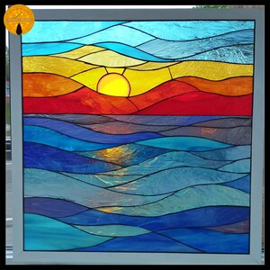 Può includere: Vetrata artistica raffigurante un tramonto sull'oceano. L'opera presenta una vibrante tavolozza di colori blu, rossi, arancioni e gialli. Il sole è un cerchio giallo brillante e le onde dell'oceano sono stratificate in tonalità di blu.