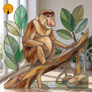 Könnte beinhalten: Ein Buntglasfenster, das einen Nasenaffen mit braunem Fell auf einem Ast sitzend zeigt. Der Affe hat eine große Nase und ist von grünen Glasblättern umgeben. Das Stück ist mit dunklen Metalllötlinien durchgehend konstruiert.