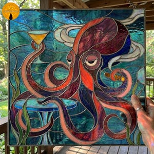 May include: Stained glass panel featuring a purple and orange octopus holding a martini glass and a cigar. The octopus is set against a teal and blue background with stylized waves and a small table. The artwork is framed in a dark metal.