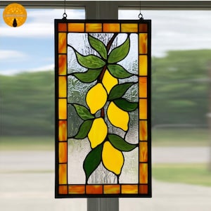 Può includere: Pannello per finestra in vetro colorato raffigurante un ramo di limone con limoni gialli e foglie verdi. Il pannello ha un bordo nero e un bordo arancione e giallo in stile mosaico. Progettato per essere appeso.