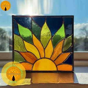 Peut inclure: Un panneau carré en vitrail représentant un tournesol. Les pétales de la fleur sont jaunes, oranges et verts, sur un fond bleu foncé. Le panneau est encadré de noir et est placé devant une fenêtre.