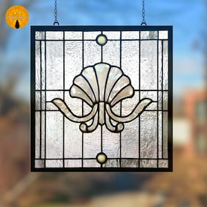 Puede incluir: Panel de ventana cuadrado de vidrieras con marco negro y diseño de concha. La concha es blanca e iridiscente, con un fondo texturizado. Dos pequeños acentos redondos amarillo-blanco están en la parte superior e inferior.
