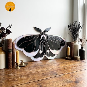 Puede incluir: Una taza de cerámica blanca con un asa negra y el texto "But First, Coffee" en negro y negrita. La taza está sobre una superficie de madera. La taza mide aproximadamente 10 cm de alto.