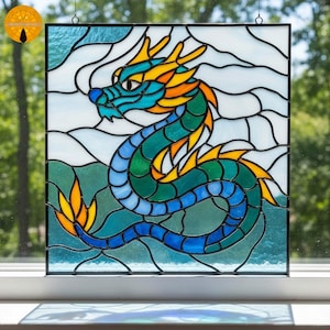 Puede incluir: Panel de vidrieras con un diseño de dragón colorido. El dragón tiene una cabeza turquesa, cuerpo verde y detalles amarillos y naranjas. El fondo incluye vidrio blanco y azul, creando una pieza decorativa vibrante.