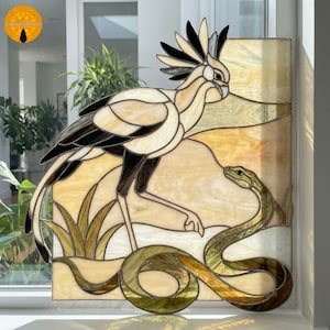 Peut inclure: Un panneau en vitrail représentant un oiseau secrétaire avec une crête proéminente debout au-dessus d'un serpent enroulé. L'oiseau présente des pièces de verre crème, blanc et noir, tandis que le serpent est rendu dans des tons de vert et d'or. Le fond se compose de panneaux de verre jaune clair et crème.