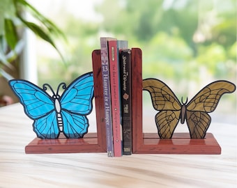 May include: Butterfly-shaped bookends in a rich mahogany finish. One bookend features a blue butterfly, the other a gold butterfly. The bookends hold several books, including "Hamster in a Hamper" and "The Bed and Breakfast Star".